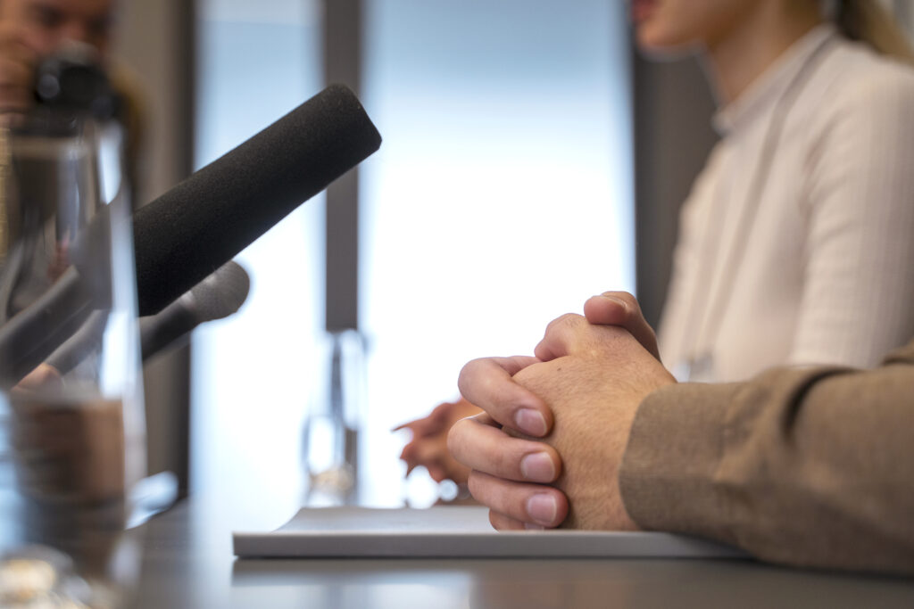 Conférence de presse, mains croisées.