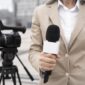 Journaliste avec microphone devant caméra