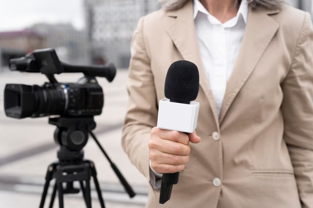 Journaliste avec microphone devant caméra