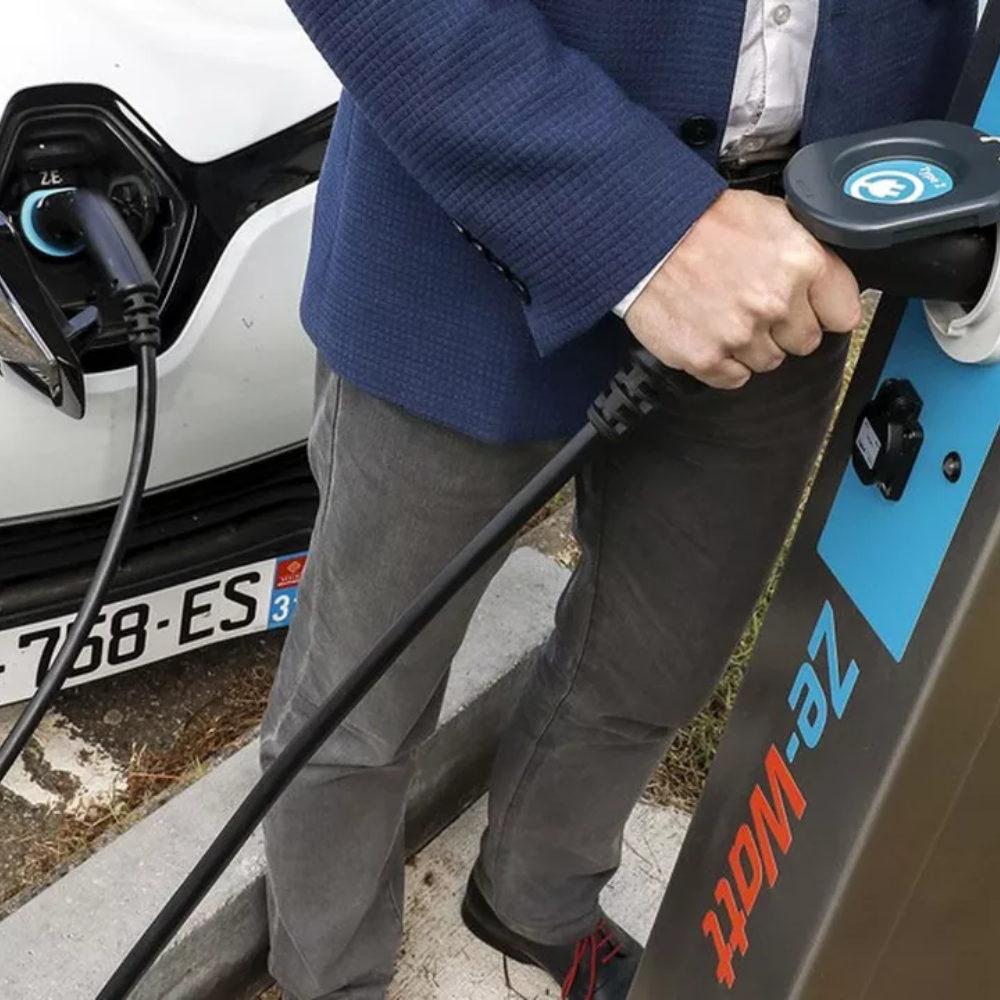 un homme fait charger sa voiture électrique